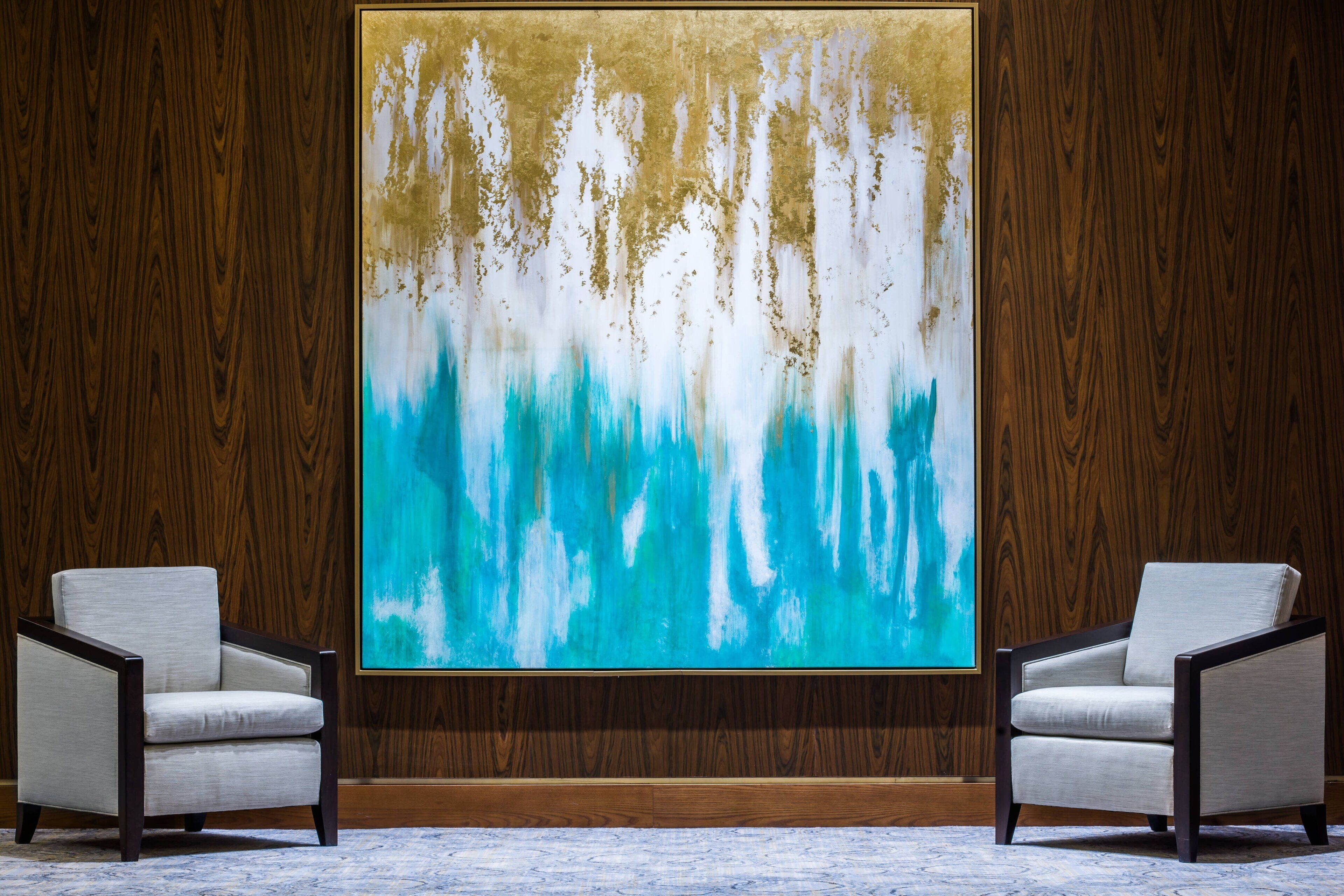 A room with a large abstract painting on the wall, two armchairs, and wooden paneling.