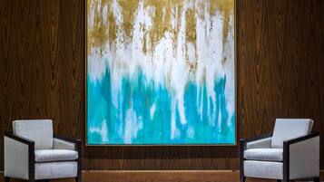 A room with a large abstract painting on the wall, two armchairs, and wooden paneling.