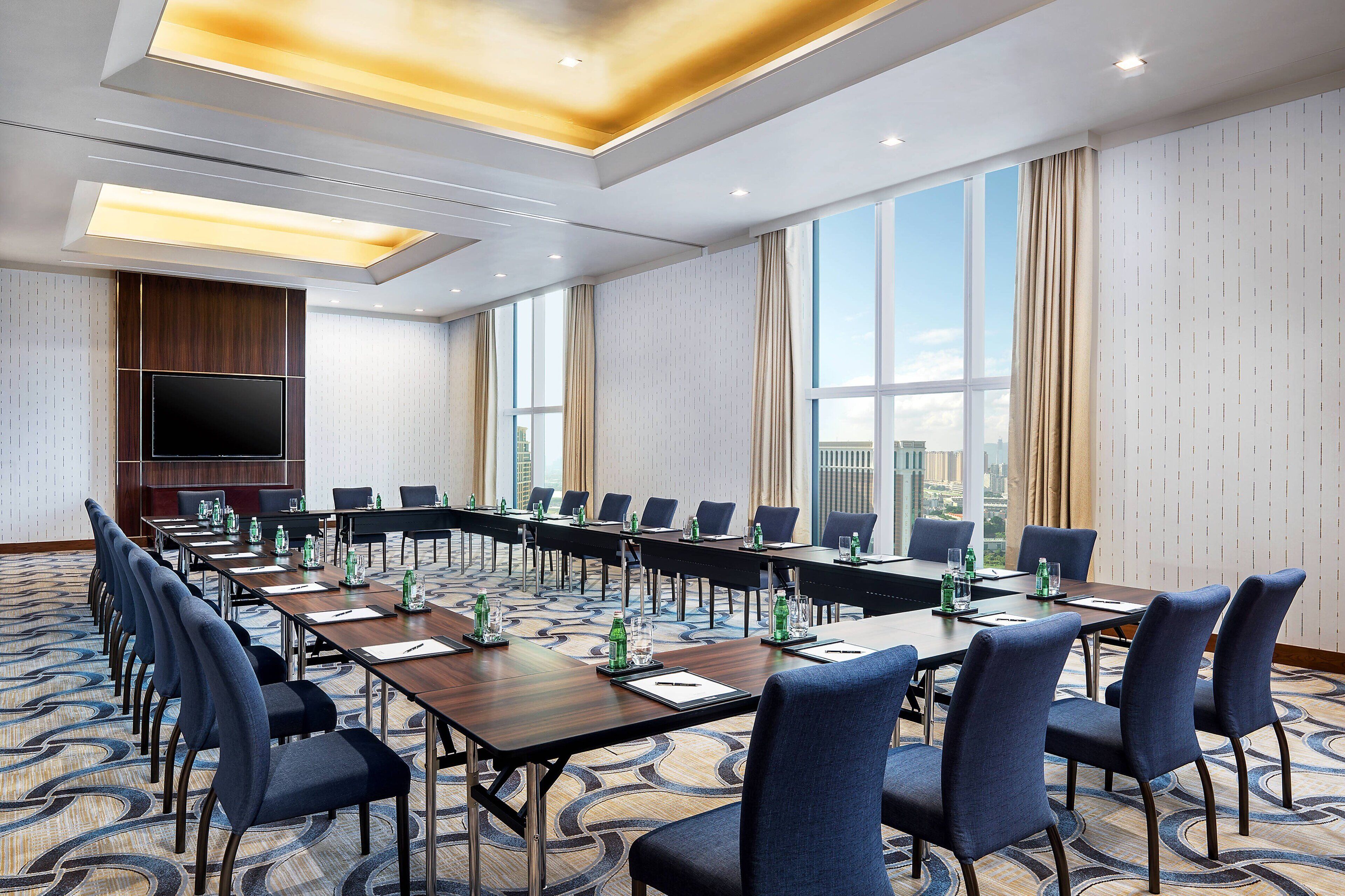 A conference room with a long table, chairs, and a TV screen.