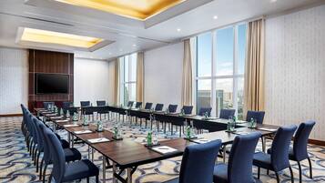 A conference room with a long table, chairs, and a TV screen.