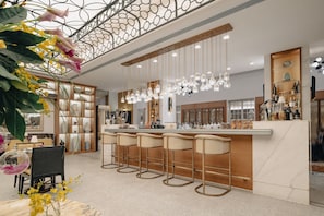 A modern bar area with a marble countertop, hanging pendant lights, and bar stools.