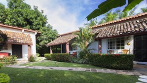 A courtyard with a tiled roof, a pathway, and a well-maintained lawn. - Villa Botero By Casa Mojito B&B (Rio Hato)