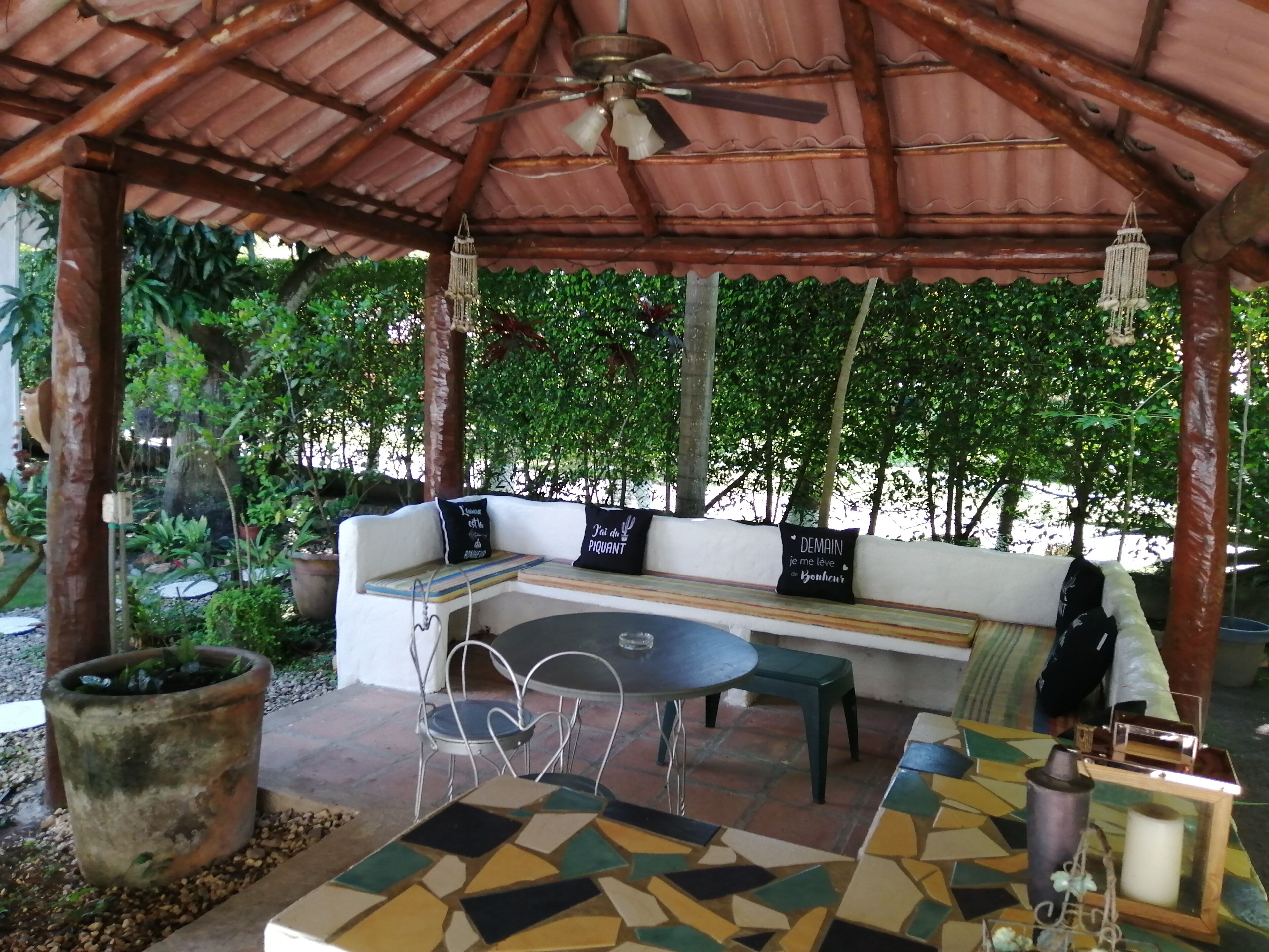 Un área de estar al aire libre con un banco de madera, una mesa y sillas.