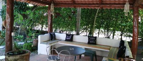 Un área de estar al aire libre con un banco de madera, una mesa y sillas.