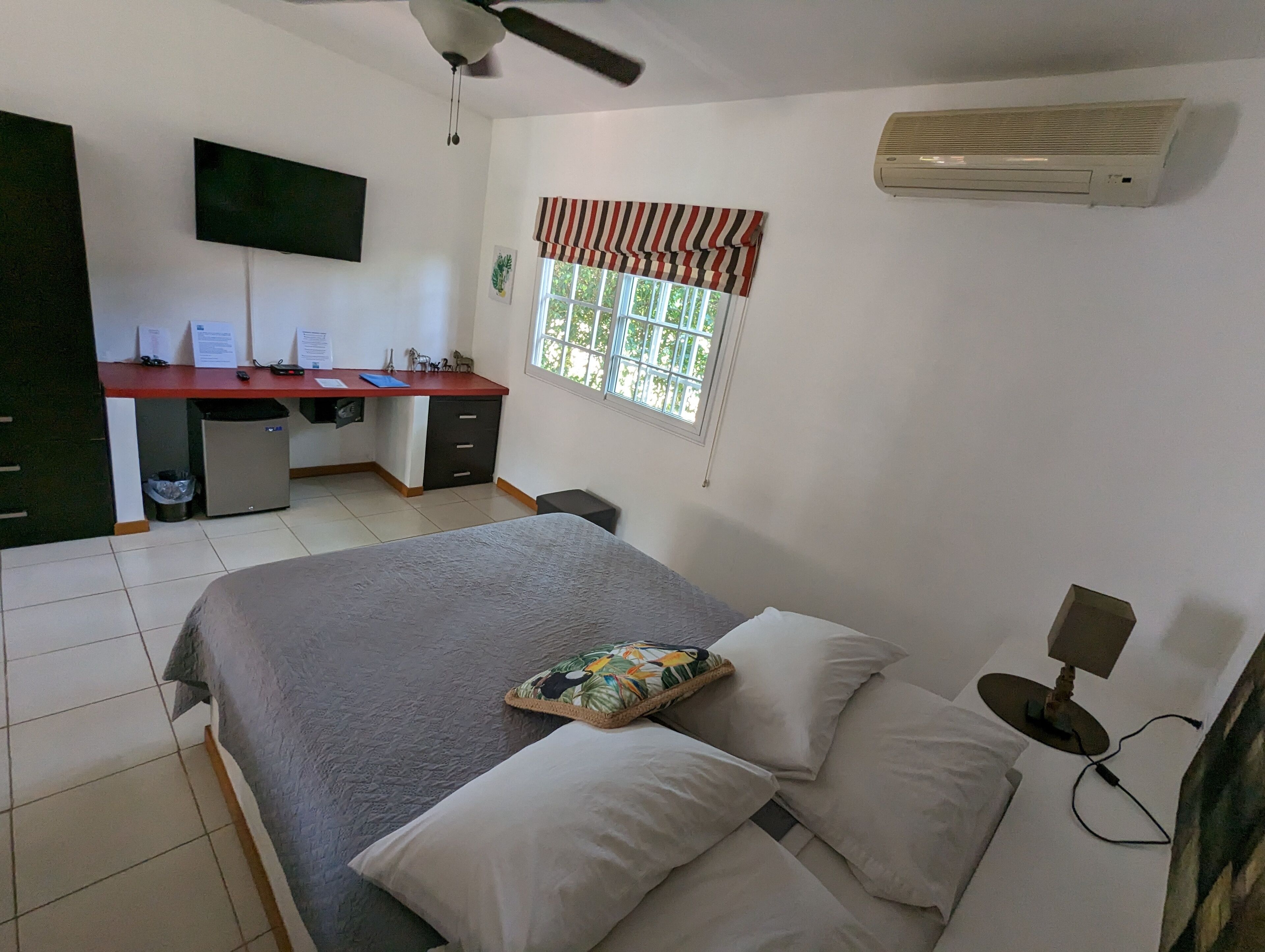 Ein Schlafzimmer mit Bett, Schreibtisch, Stuhl, Fernseher und Klimaanlage.
