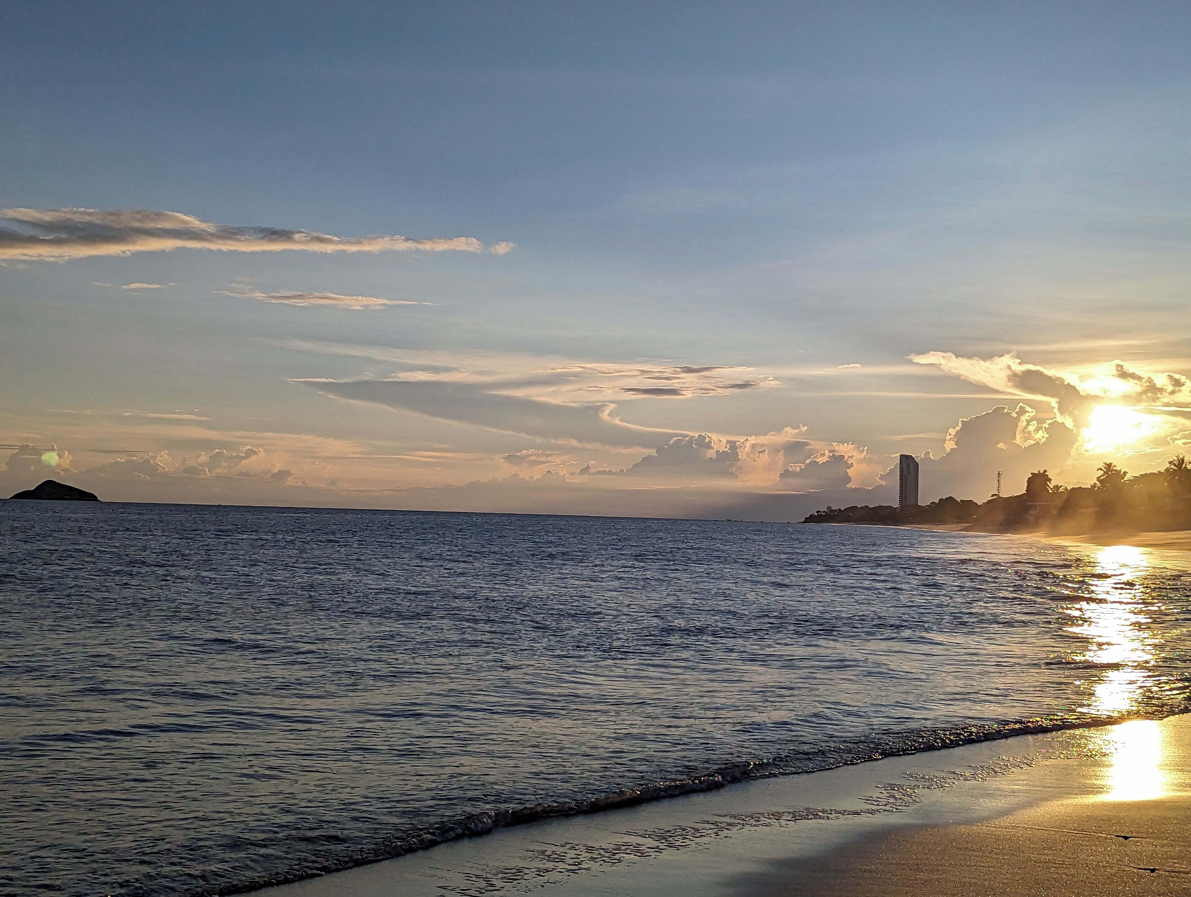 Une plage aux eaux calmes, où l’on peut admirer le coucher du soleil.