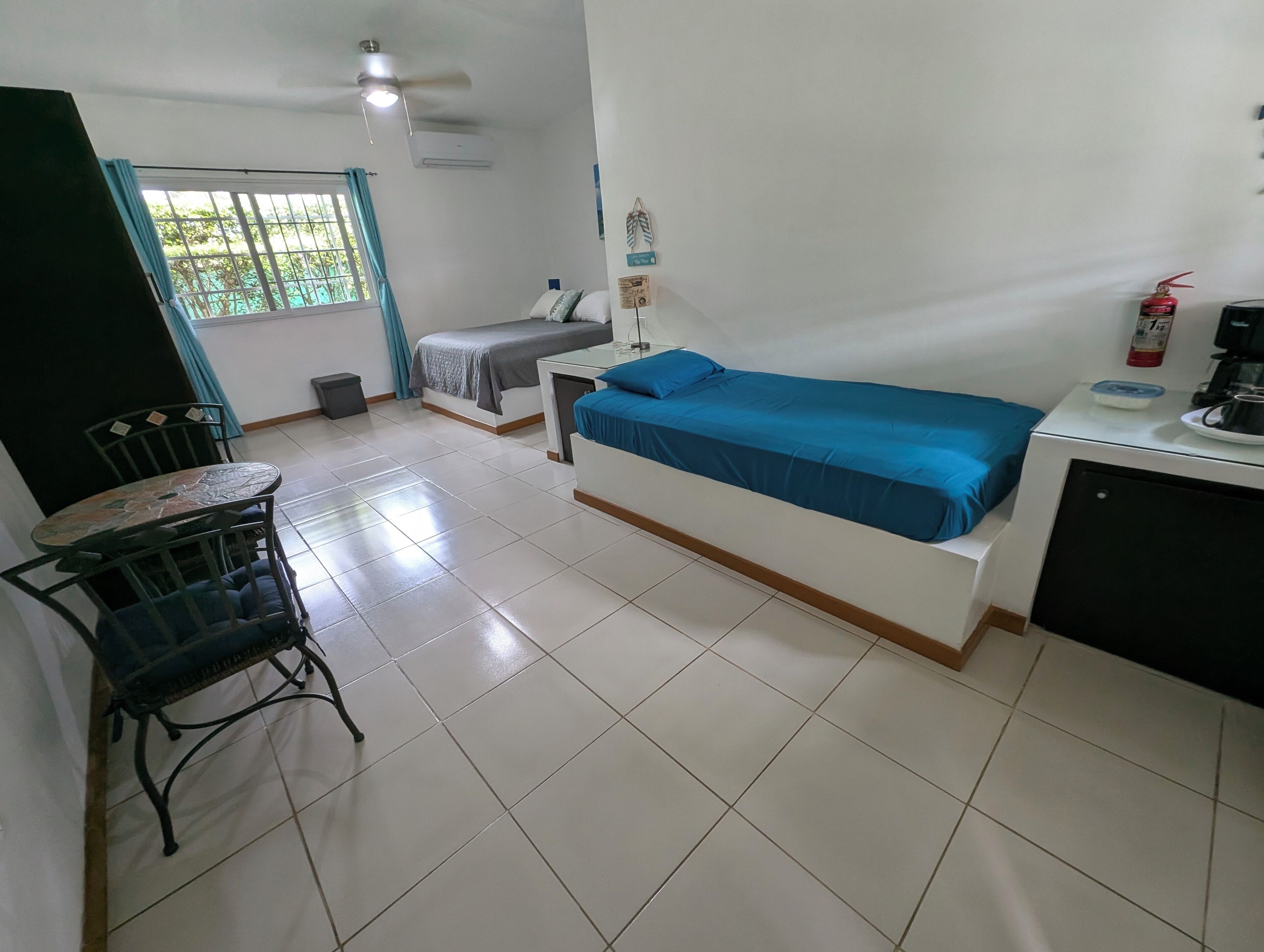 A small, clean room with a bed, a desk, a chair, and a window with curtains.