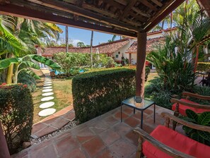 A covered patio area with a stone pathway leading to a pool, surrounded by lush greenery and a well-maintained hedge. - Villa Botero By Casa Mojito B&B (Rio Hato)
