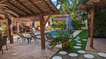 A poolside area with lounge chairs, a hammock, and a covered seating area.