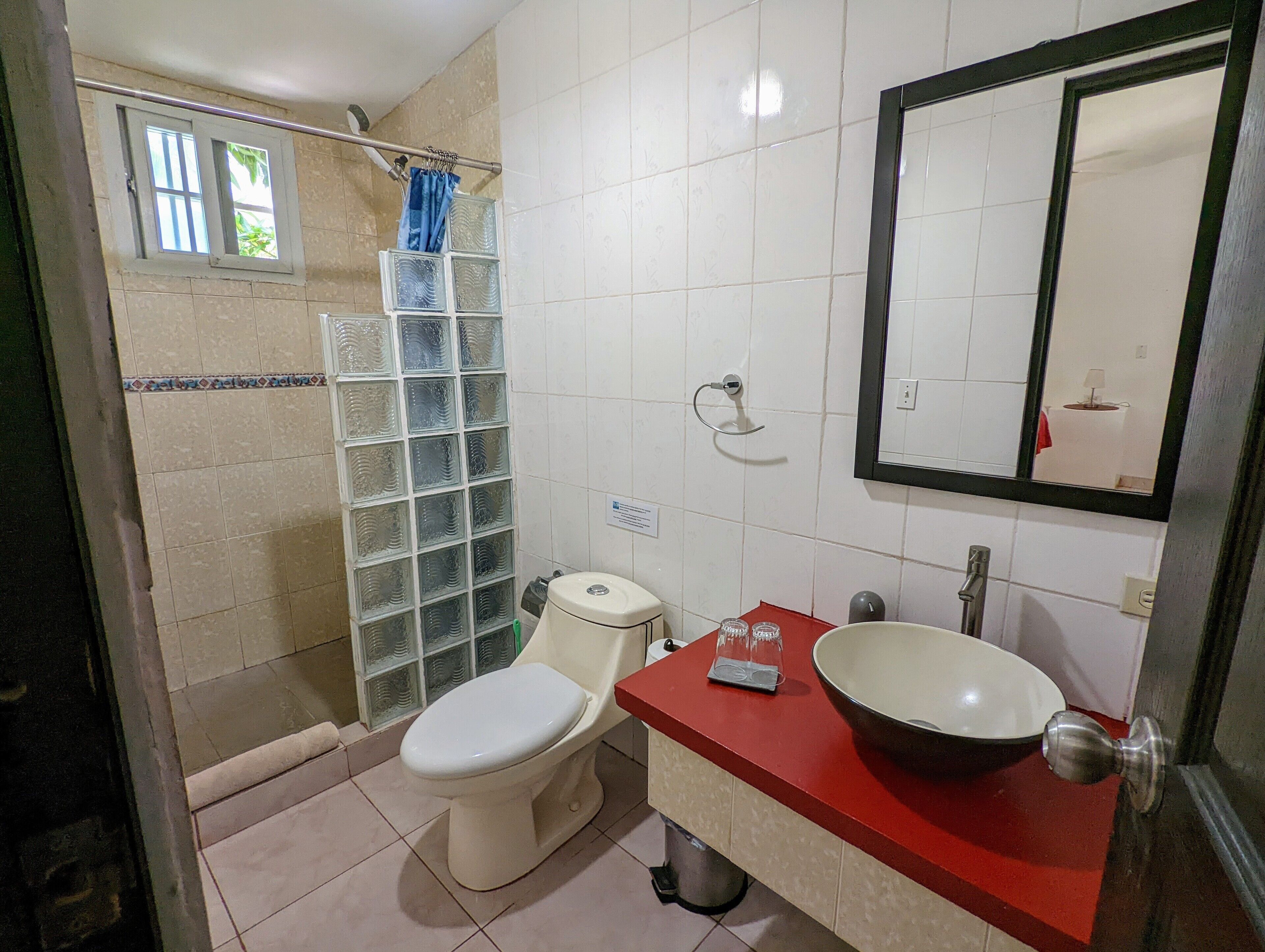 Ein Badezimmer mit Toilette, Waschbecken, Spiegel und Duschbereich.