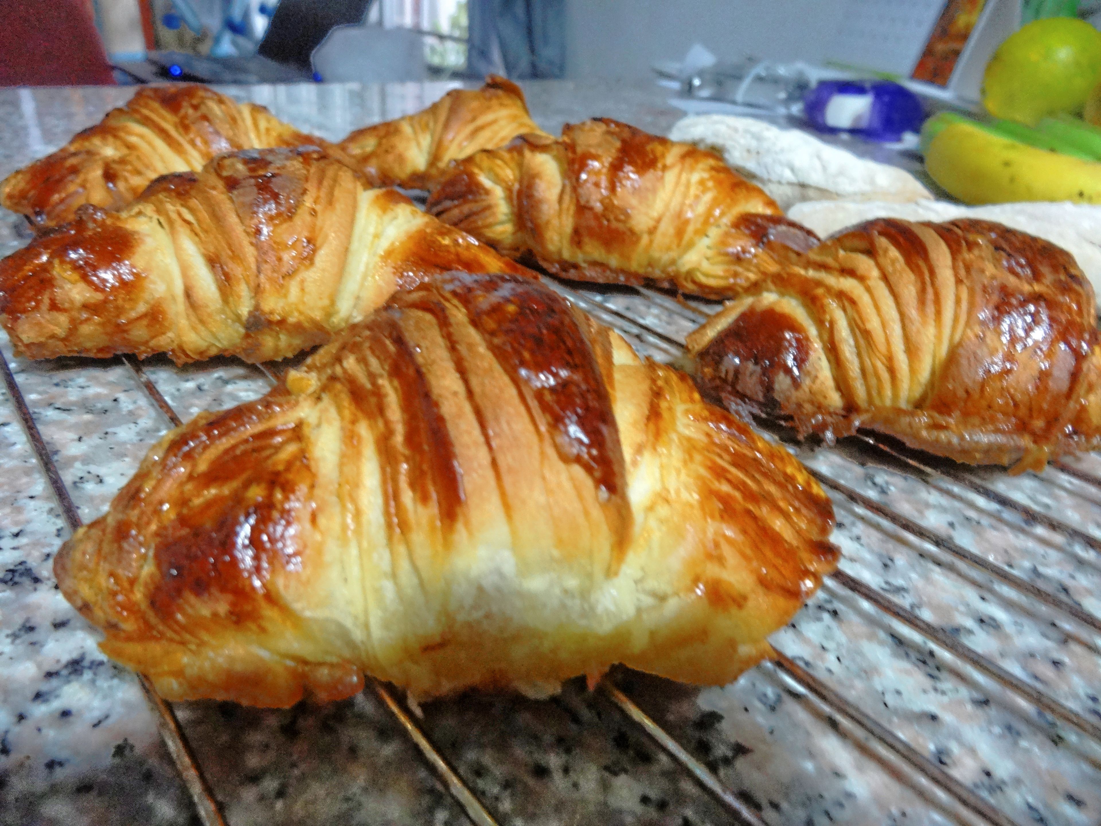 A kitchen counter with several pastries, including croissants, and a banana in the background.