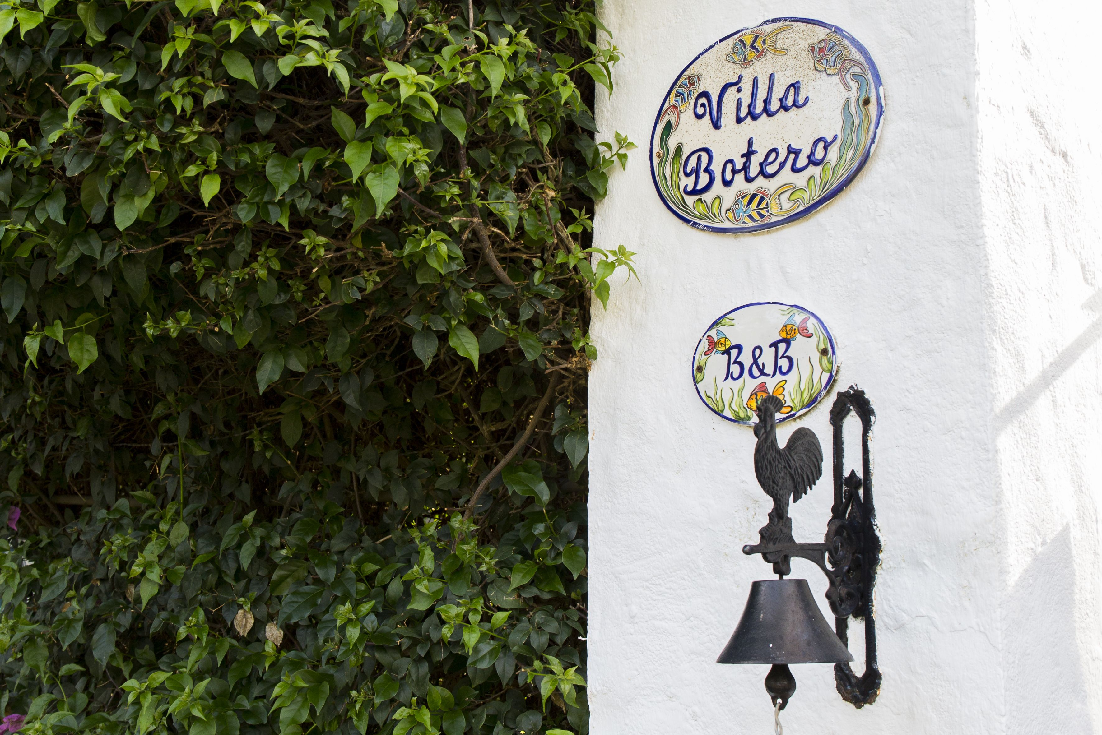 Uma parede com duas placas: 'Villa Botero' e 'B&B'.
