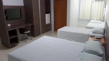 Habitación de hotel con dos camas, un escritorio con silla, televisor y armario.