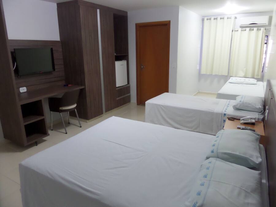Habitación de hotel con dos camas, un escritorio con silla, televisor y armario.