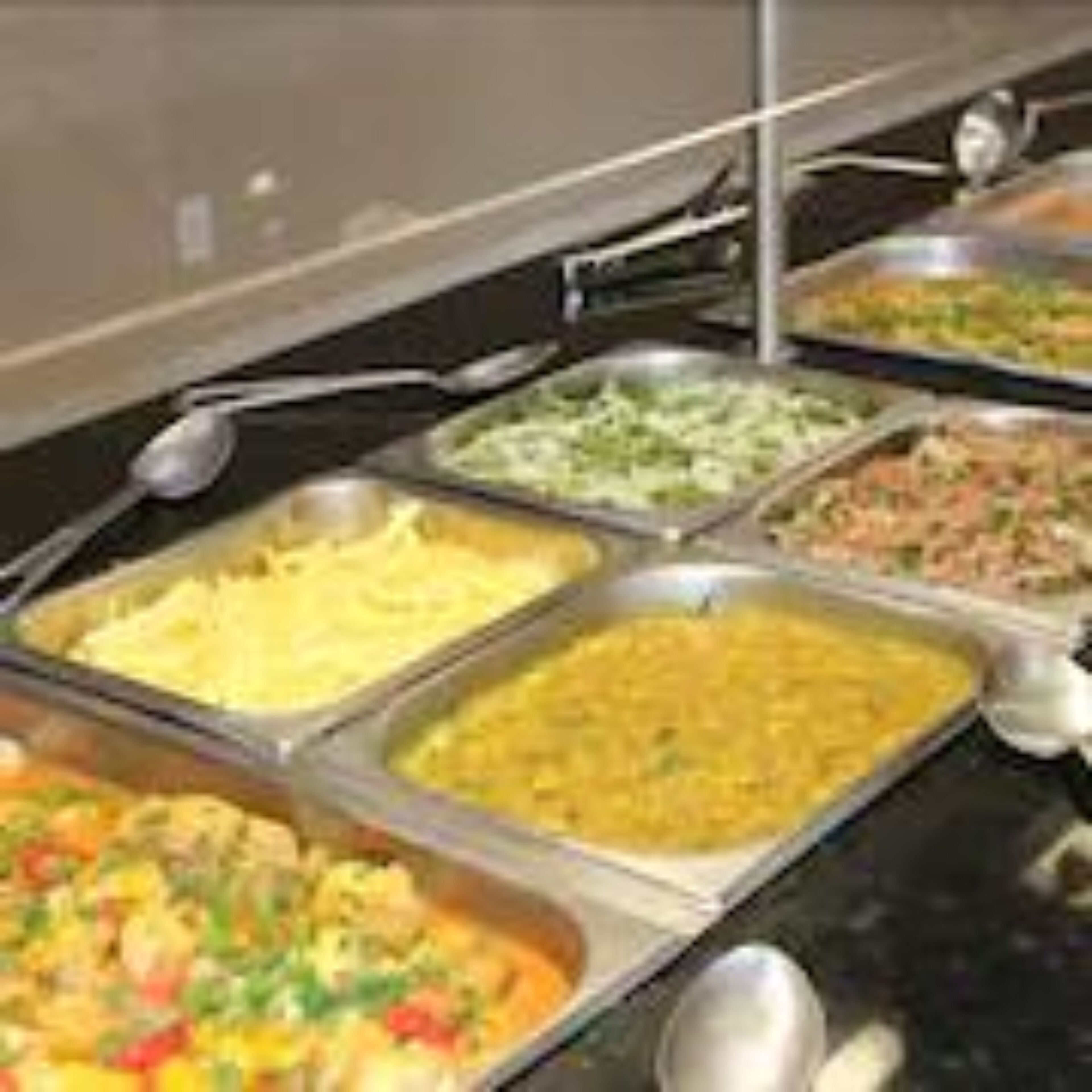 Un bufé con diversas opciones de comida, como ensaladas, platos de arroz y un pastel de carne.