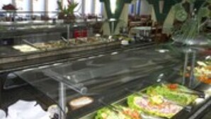 Un bufé con diversas opciones de comida, como ensaladas y carnes, en un ambiente interior bien iluminado.