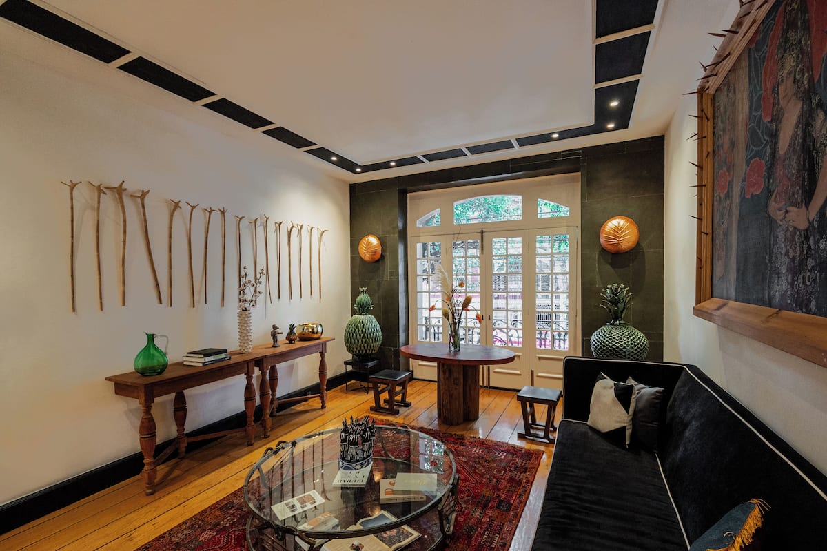Un salon moderne avec une table basse en verre, un canapé noir, un plancher en bois, une table d’appoint en bois et une grande fenêtre offrant une belle vue.
