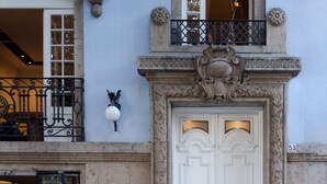 Un bâtiment doté d’une porte blanche à deux battants, d’un balcon orné de rampes en métal ouvragé et d’une petite fenêtre située au-dessus de la porte.