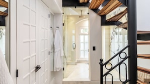 Un intérieur moderne avec un escalier, une porte blanche dotée d’un porte-serviettes et une douche en verre.