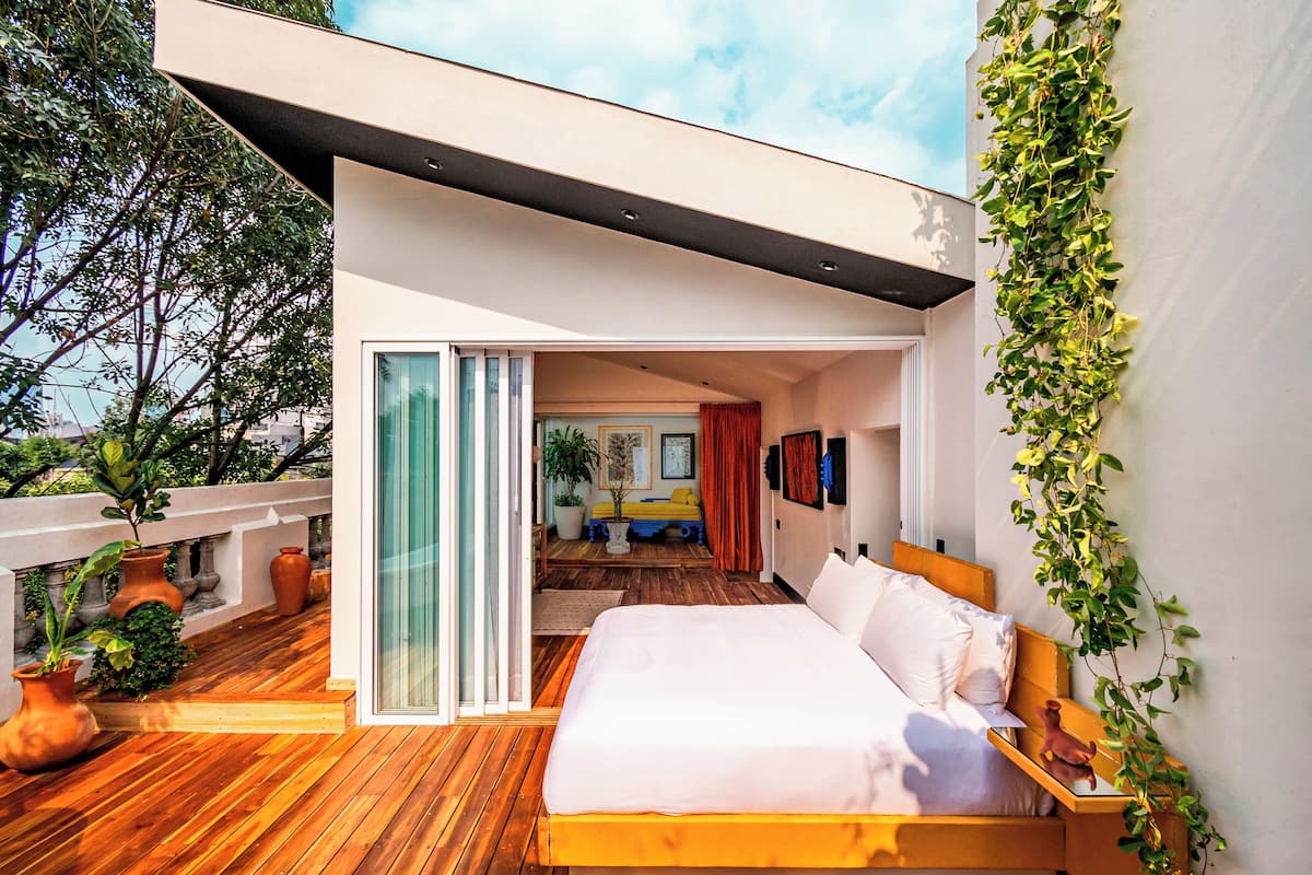 Une chambre moderne avec un plancher en bois, un grand lit et une vue sur l’extérieur.