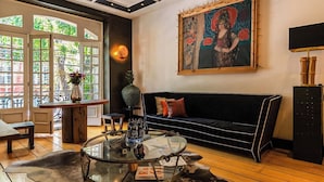 Un salon moderne avec une table basse en verre, un canapé noir et un tableau accroché au mur.