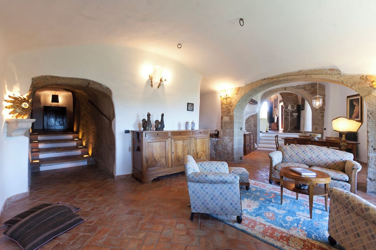 Amplia sala de estar con chimenea de piedra, un aparador de madera y un conjunto de sofás.