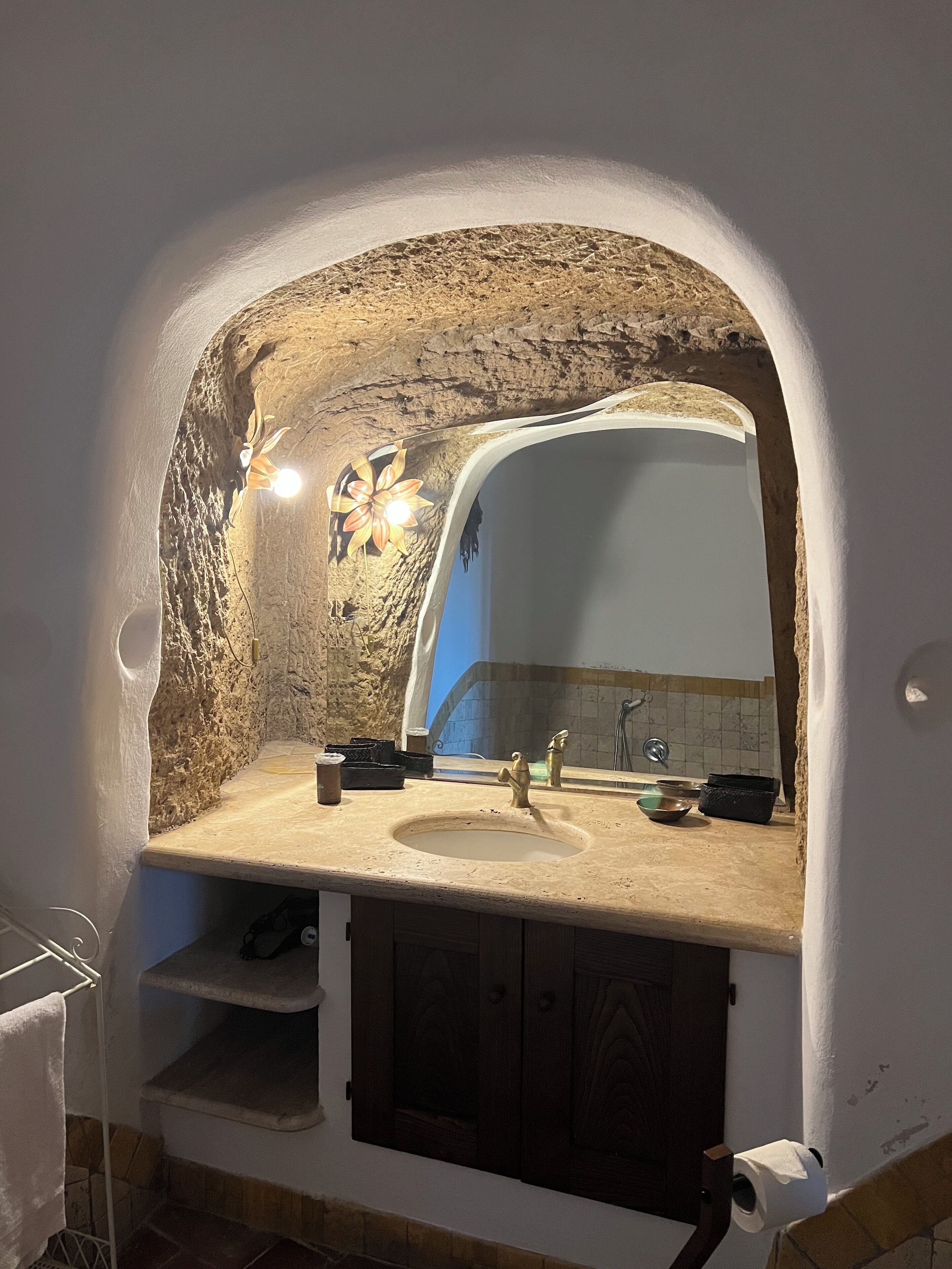 Ein Badezimmer mit Stehwand, Waschbecken, Spiegel und Handtuchhalter.
