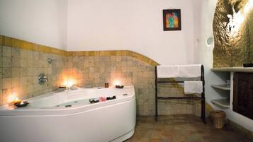 A bathroom with a large bathtub, a towel rack, and a shelf with toiletries.