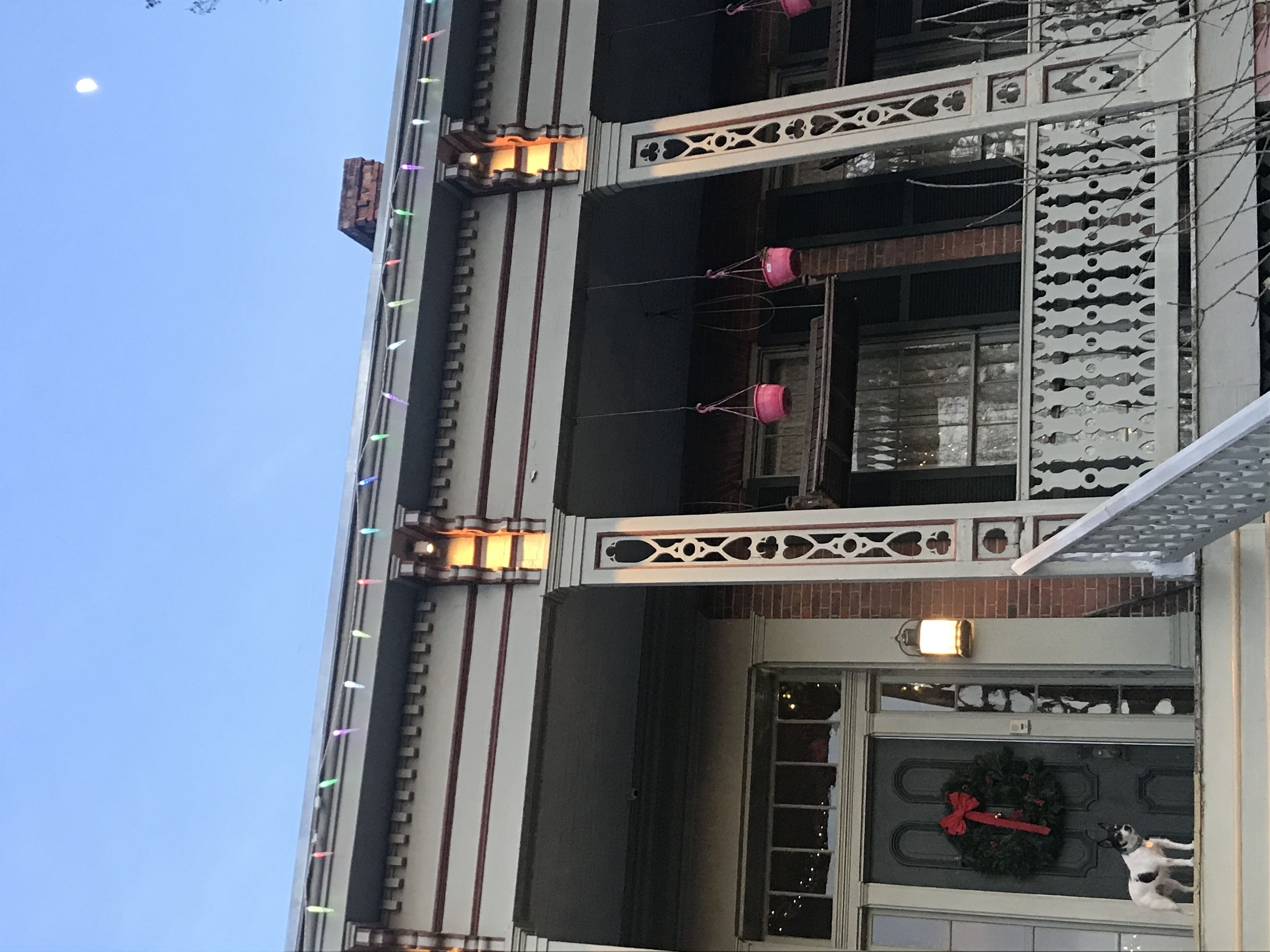 Um edifício com várias varandas, grades decorativas e uma janela com uma guirlanda.