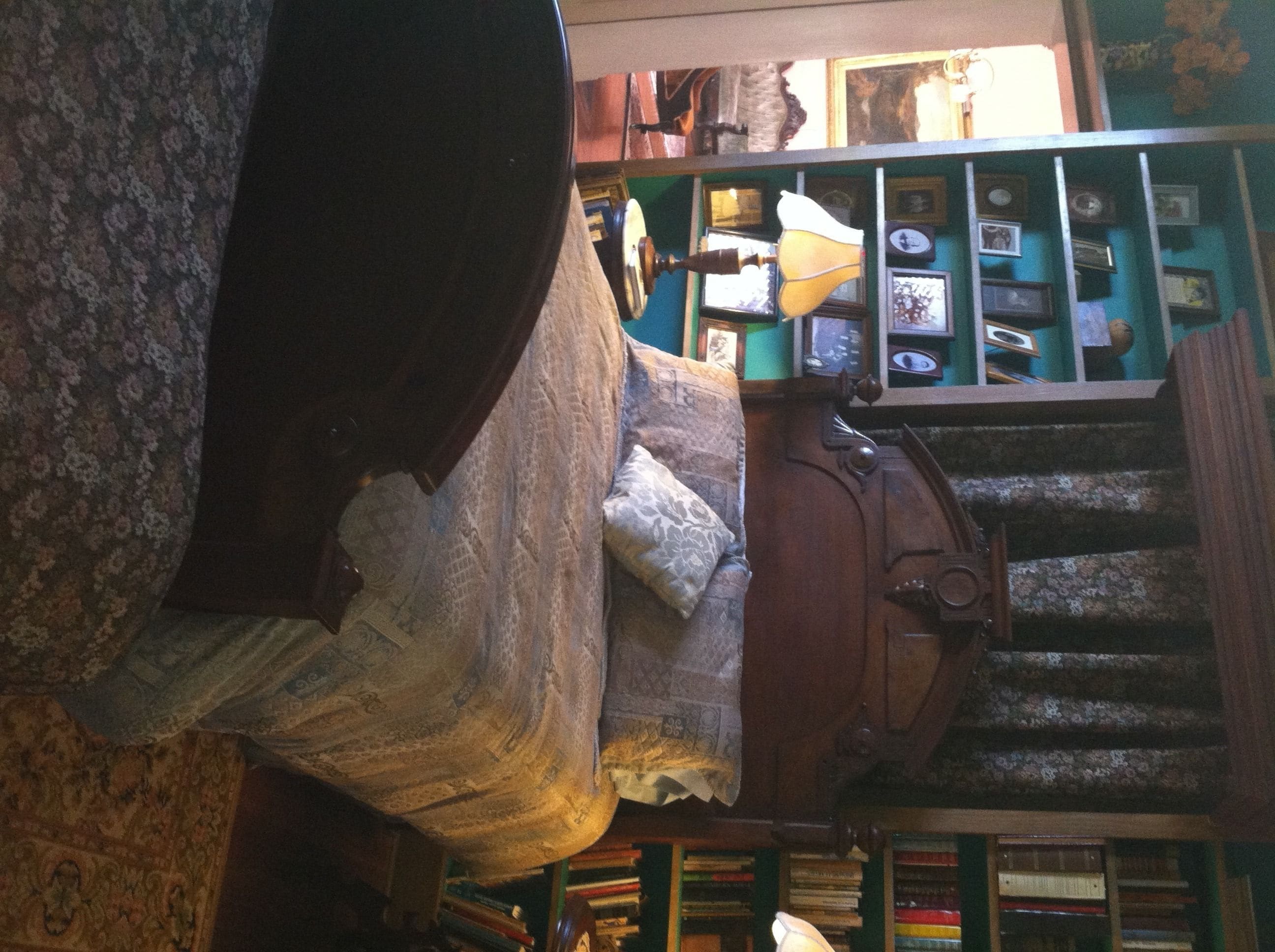 Una habitación con una cama, cabecera de madera, una estantería y una escalera.