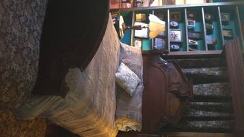 Una habitación con una cama, cabecera de madera, una estantería y una escalera.