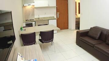 A compact living space with a kitchenette, a dining area with two chairs, and a sofa.