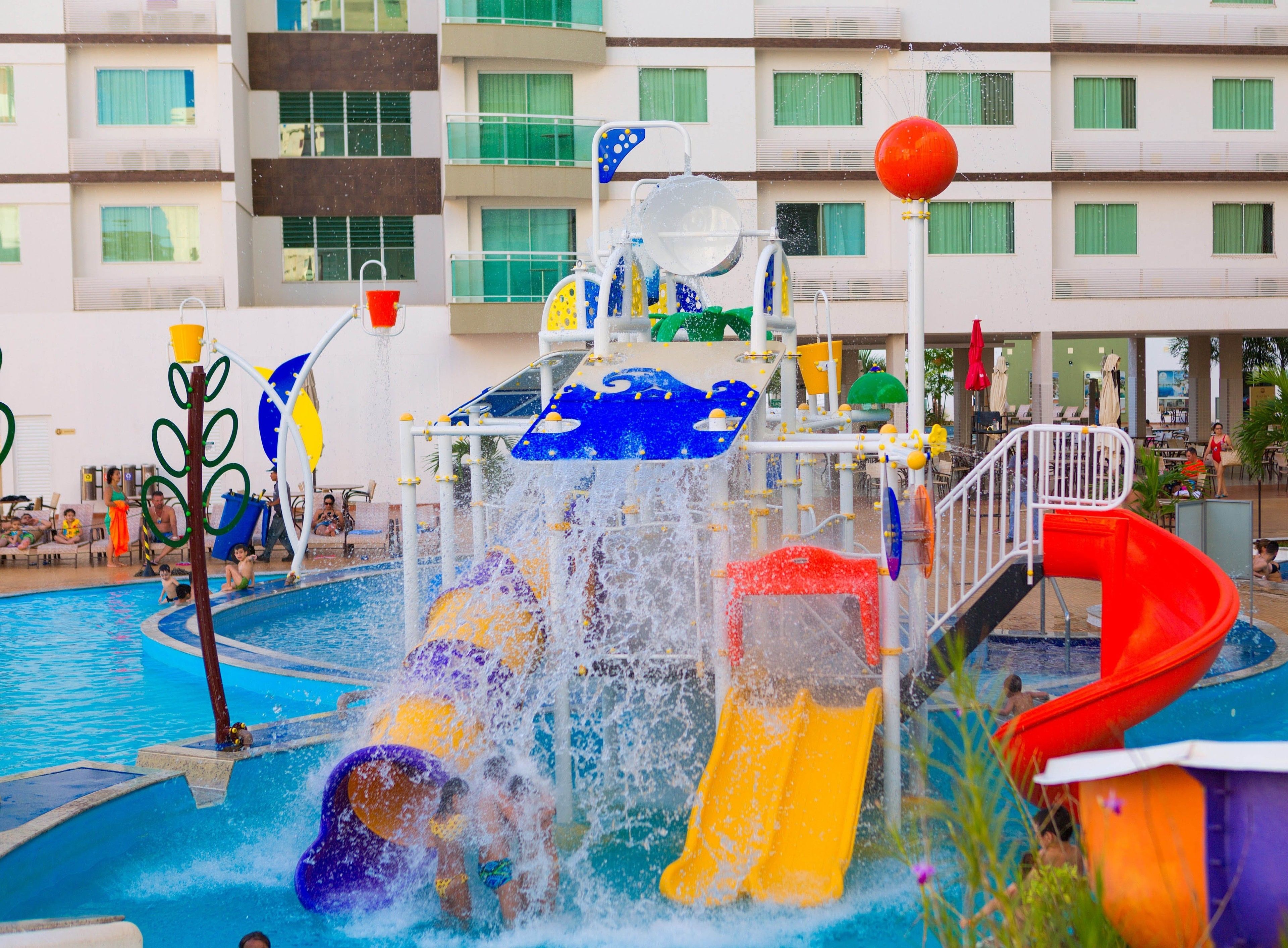 A water park with multiple slides and water features, surrounded by a pool and a building with balconies.