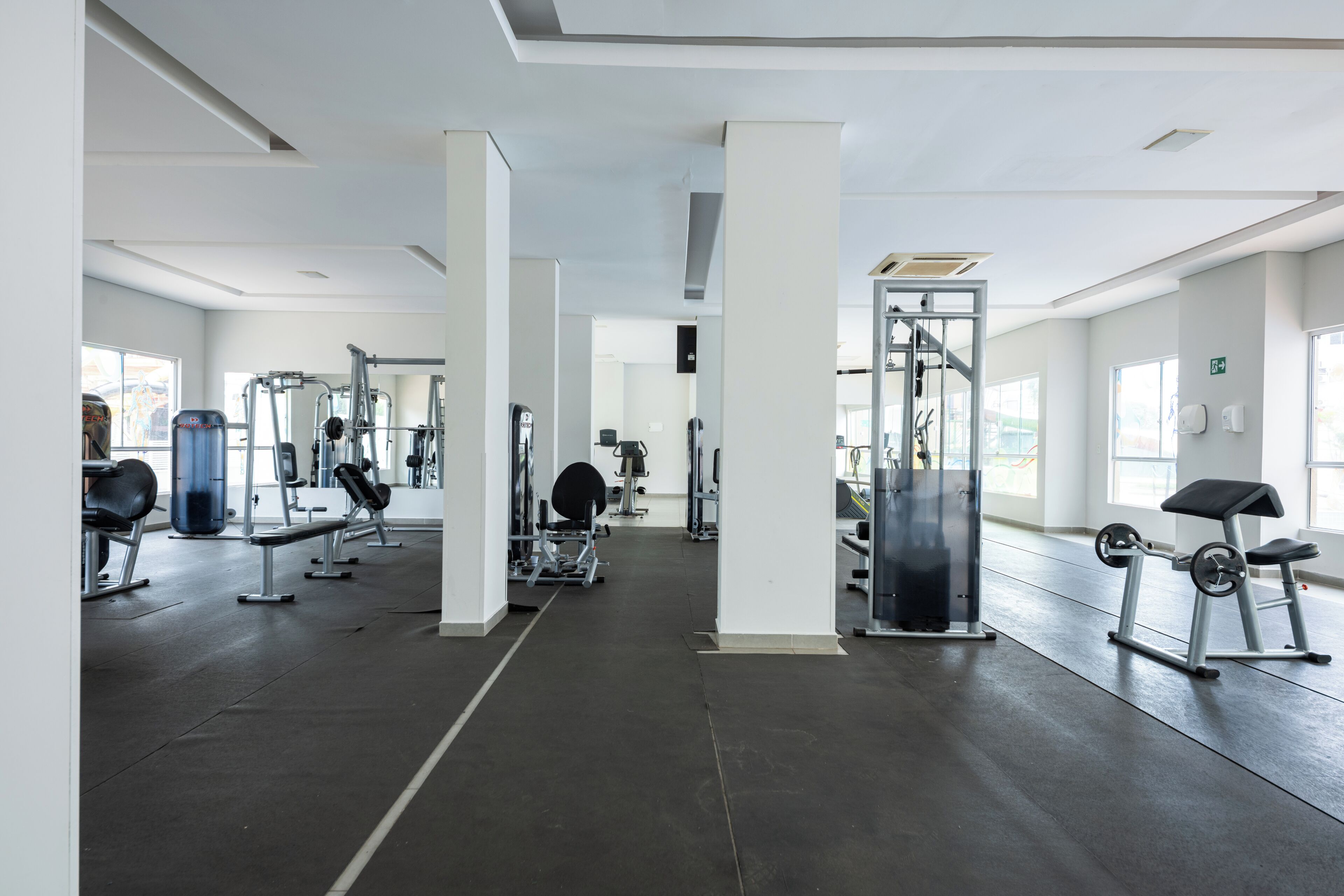 Uma academia ampla com diversos equipamentos de ginástica, amplas janelas e design moderno e limpo.