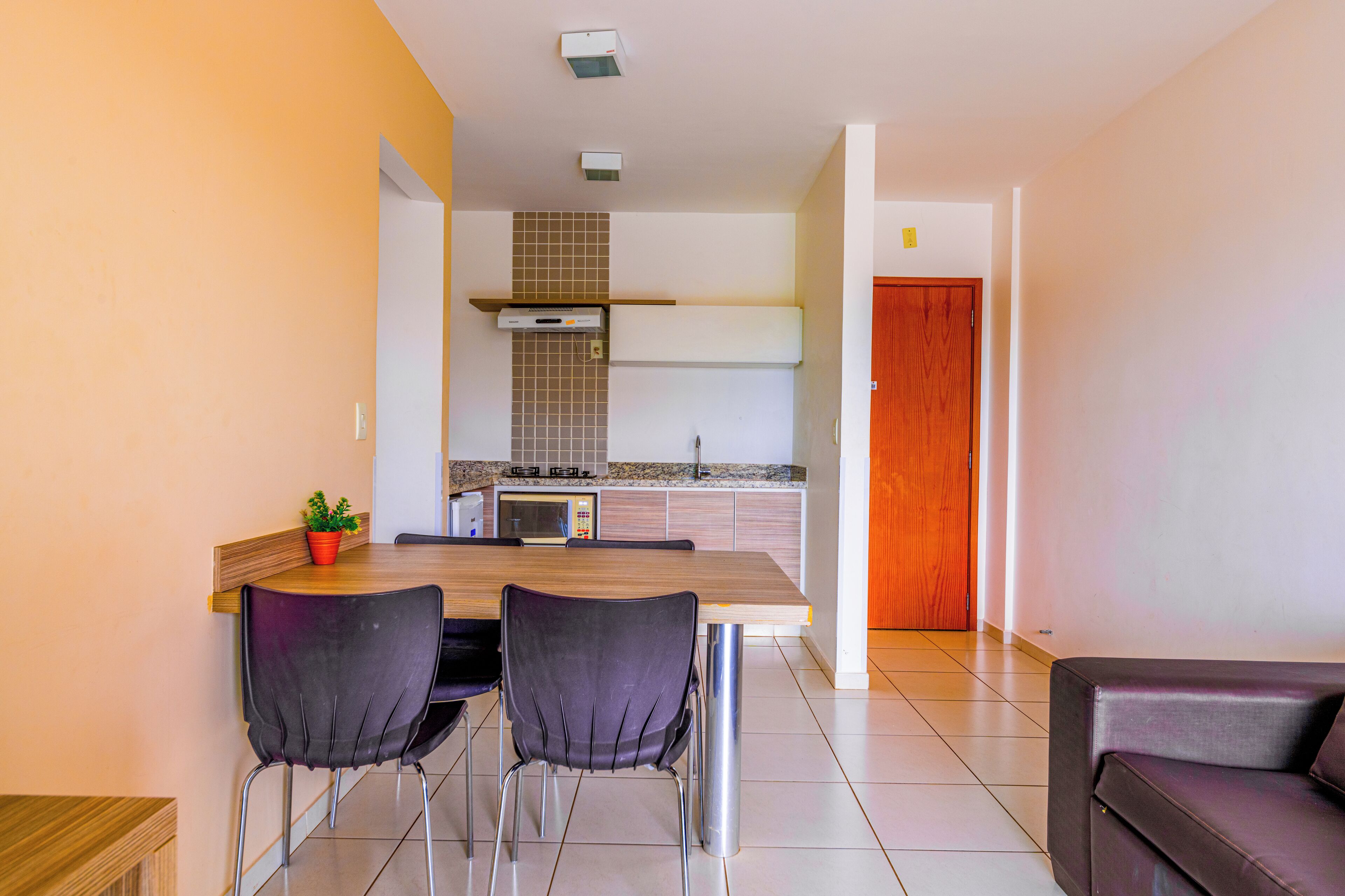 Eine moderne Küche mit Essbereich, darunter ein Holztisch, zwei Stühle und ein Blumentopf.