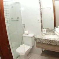 Un baño con cabina de ducha de vidrio, inodoro blanco y lavabo con encimera de granito.