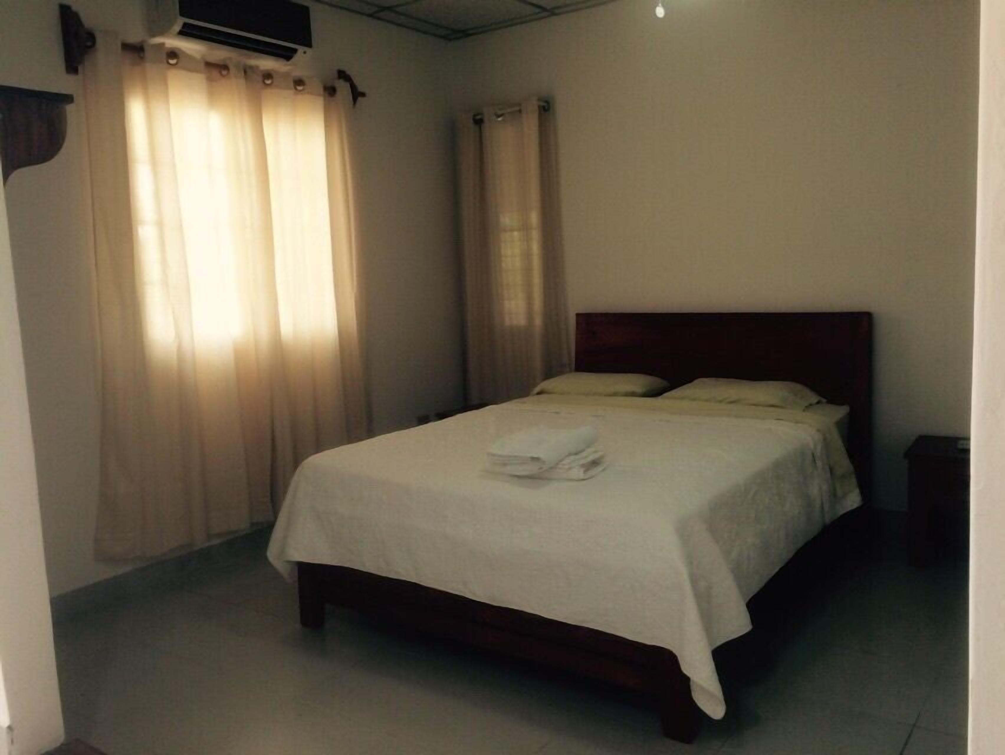 A bedroom with a single bed, a wooden headboard, and a white bedspread.