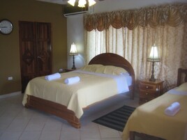Habitación de hotel con cama doble, dos mesitas de noche con lámparas, un armario de madera y un reloj de pared.
