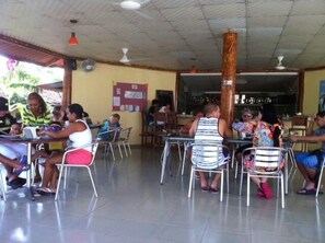 A cafeteria with tables and chairs, a bulletin board, and ceiling fans. - Casa Loma (Pedasí)