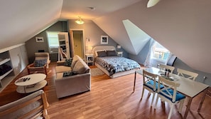Une pièce compacte et bien éclairée, comprenant un lit, un canapé, une table à manger et une chaise.