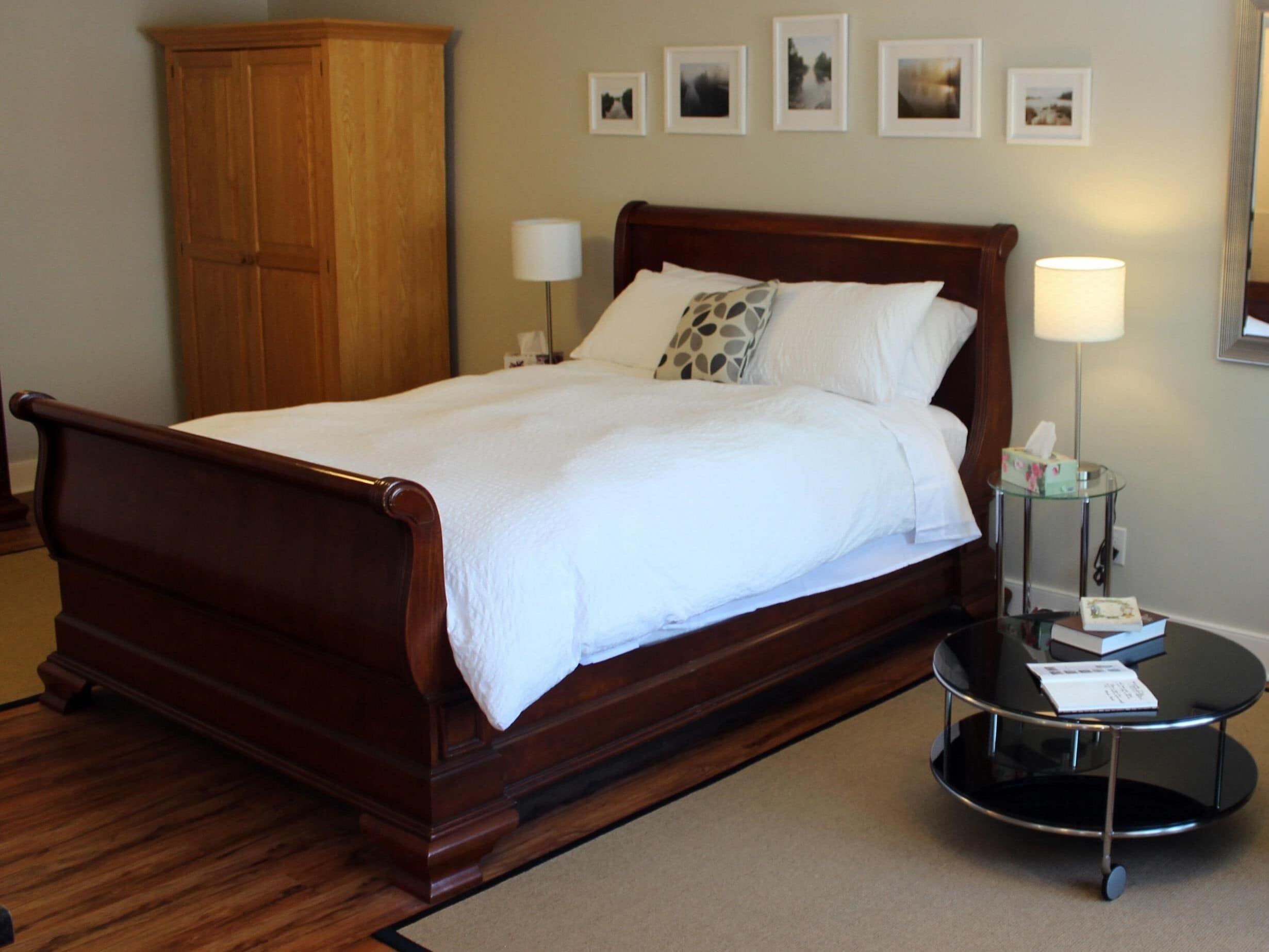 A neatly made bed with a wooden headboard, two bedside lamps, and a small table with a tissue box.