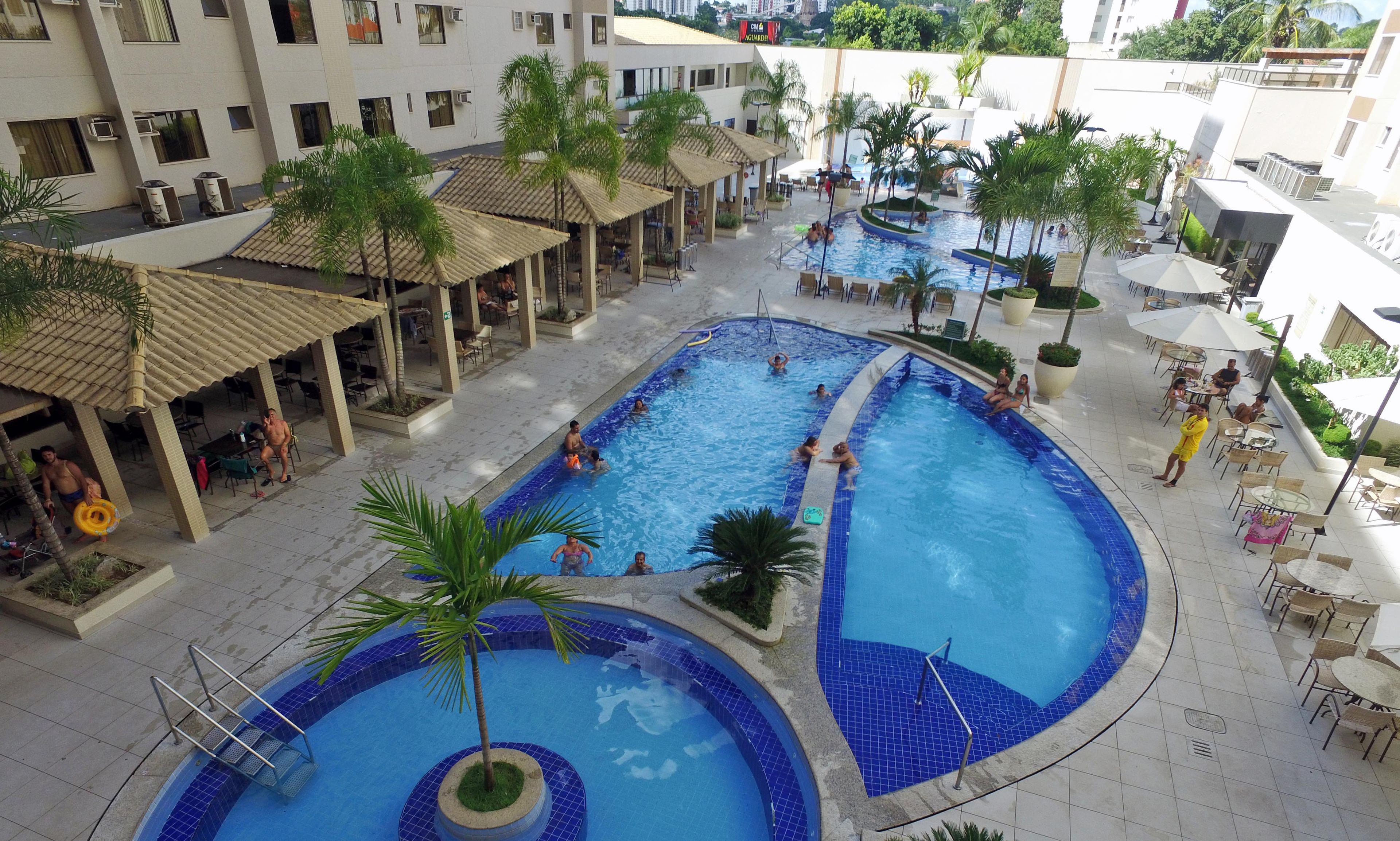 Un vaste espace extérieur doté de plusieurs piscines, de palmiers, de chaises longues et de parasols.