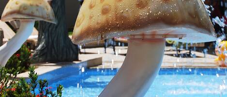 A pool area with a mushroom-shaped water feature and a tree sculpture.