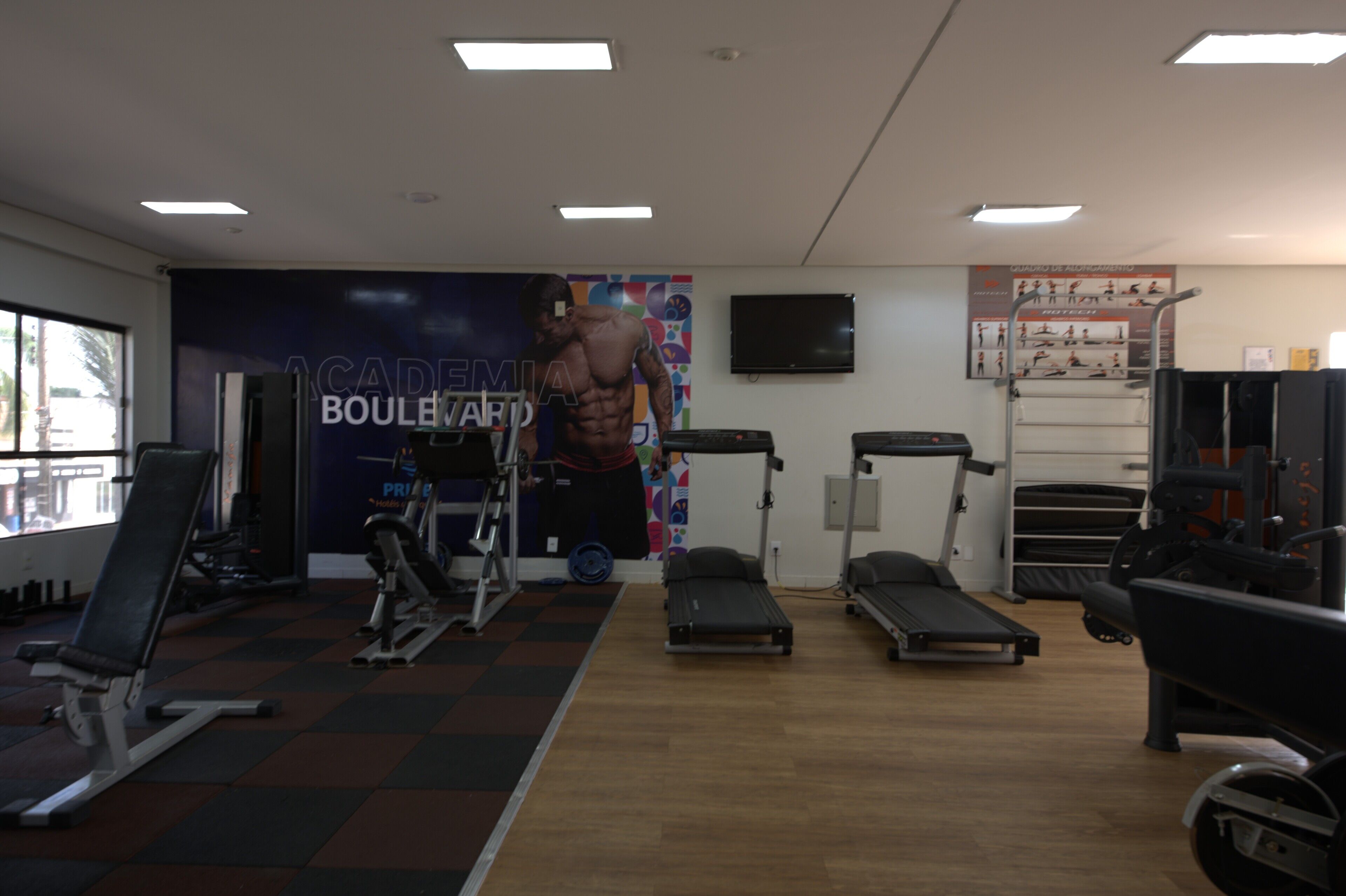 A gym with exercise equipment, a wall with a poster, and a television.