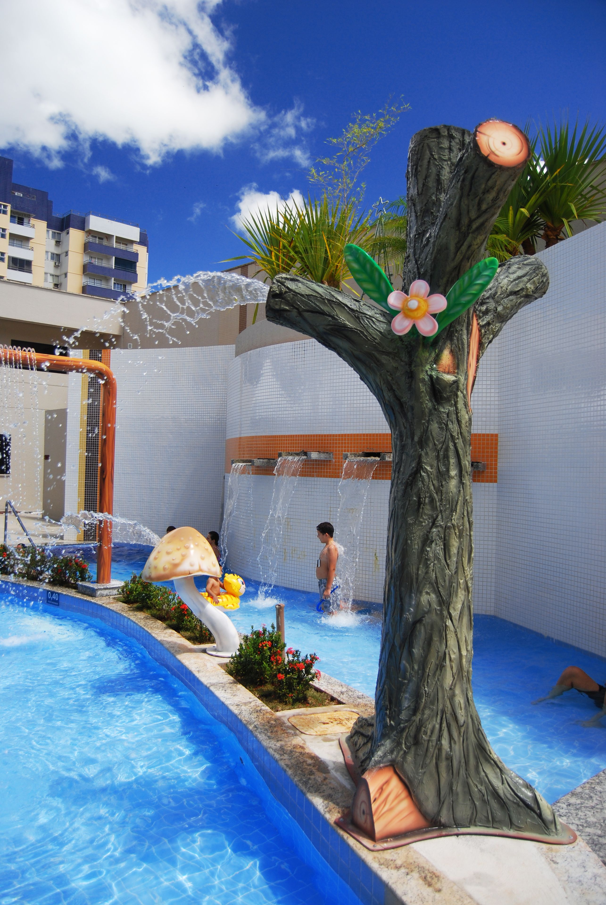 Piscina con escultura de árbol y fuente de agua.