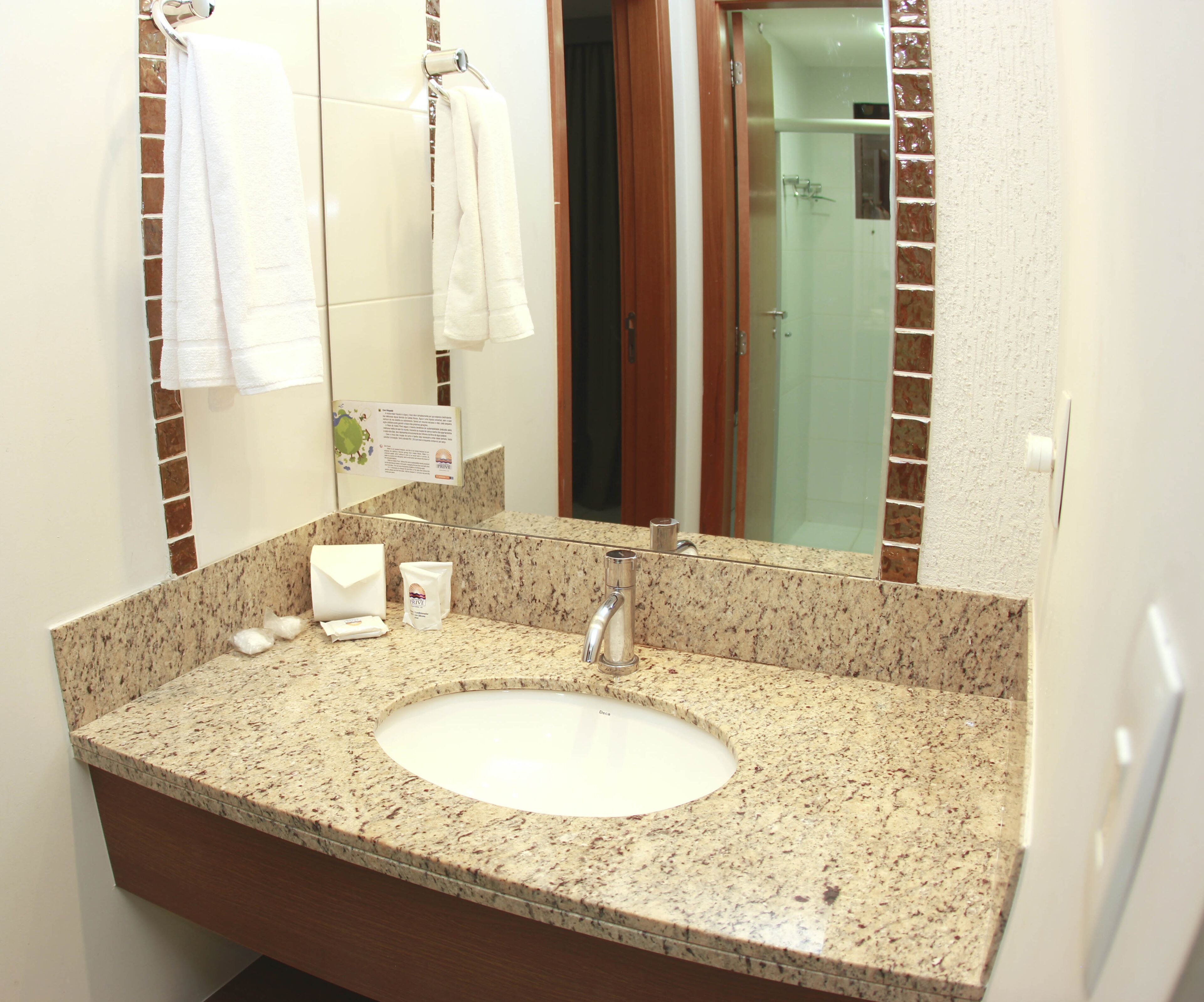 A bathroom with a granite countertop sink, a mirror, and a shower visible through an open door.