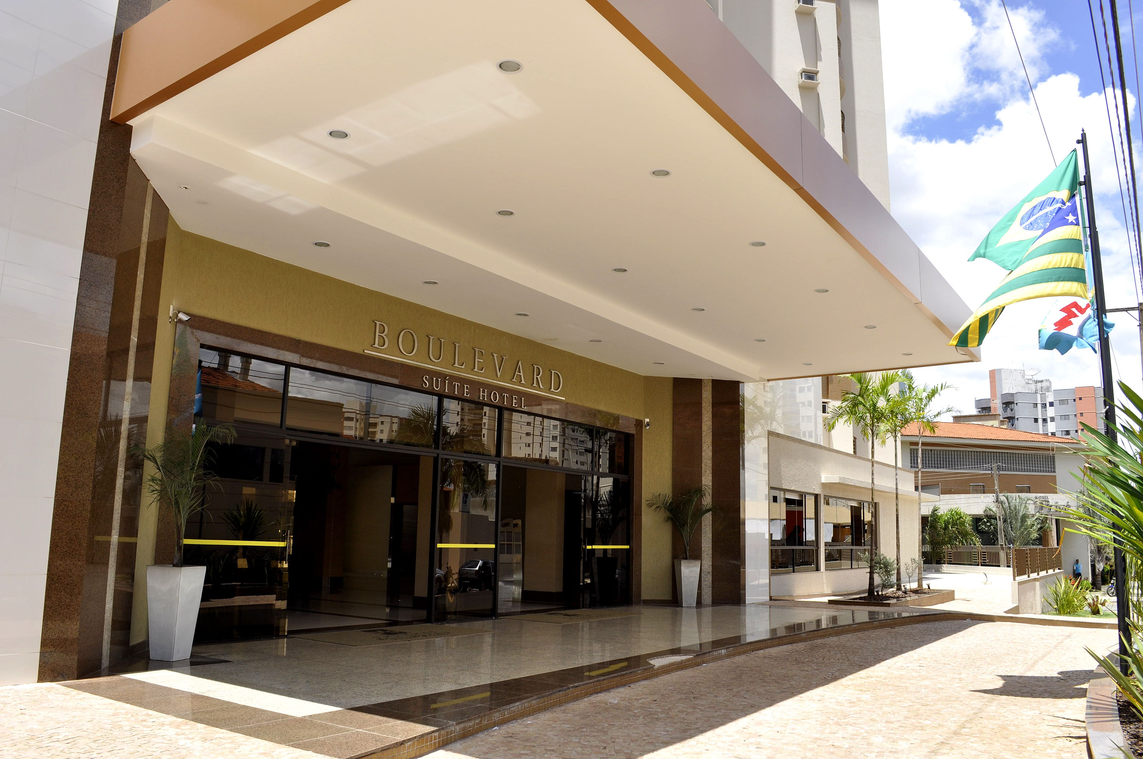 A hotel entrance with a modern design, a visible sign for the Boulevard Suite Hotel, and a flag outside.