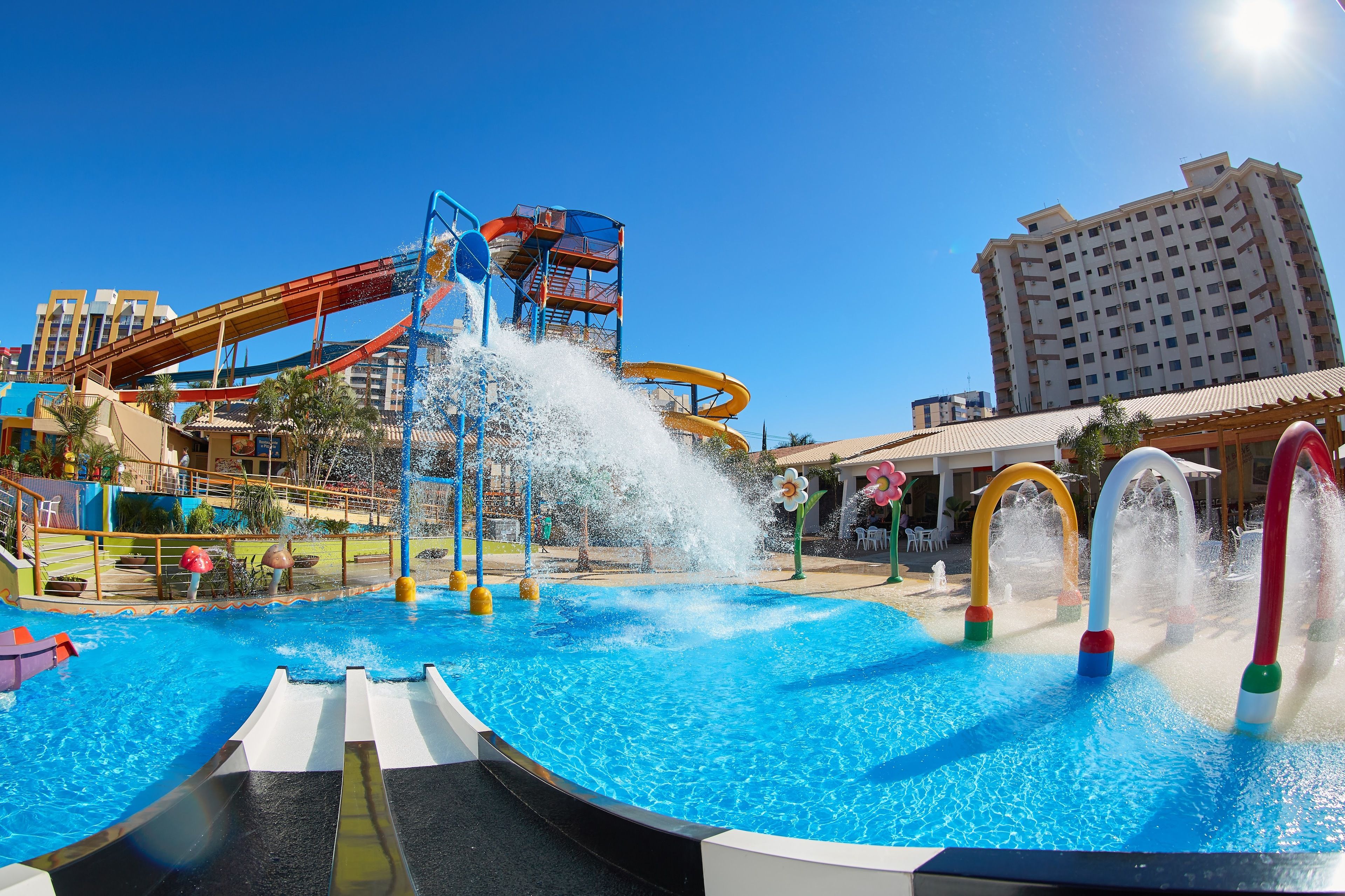 Een waterpark met een groot zwembad, glijbanen en een waterglijbaan.