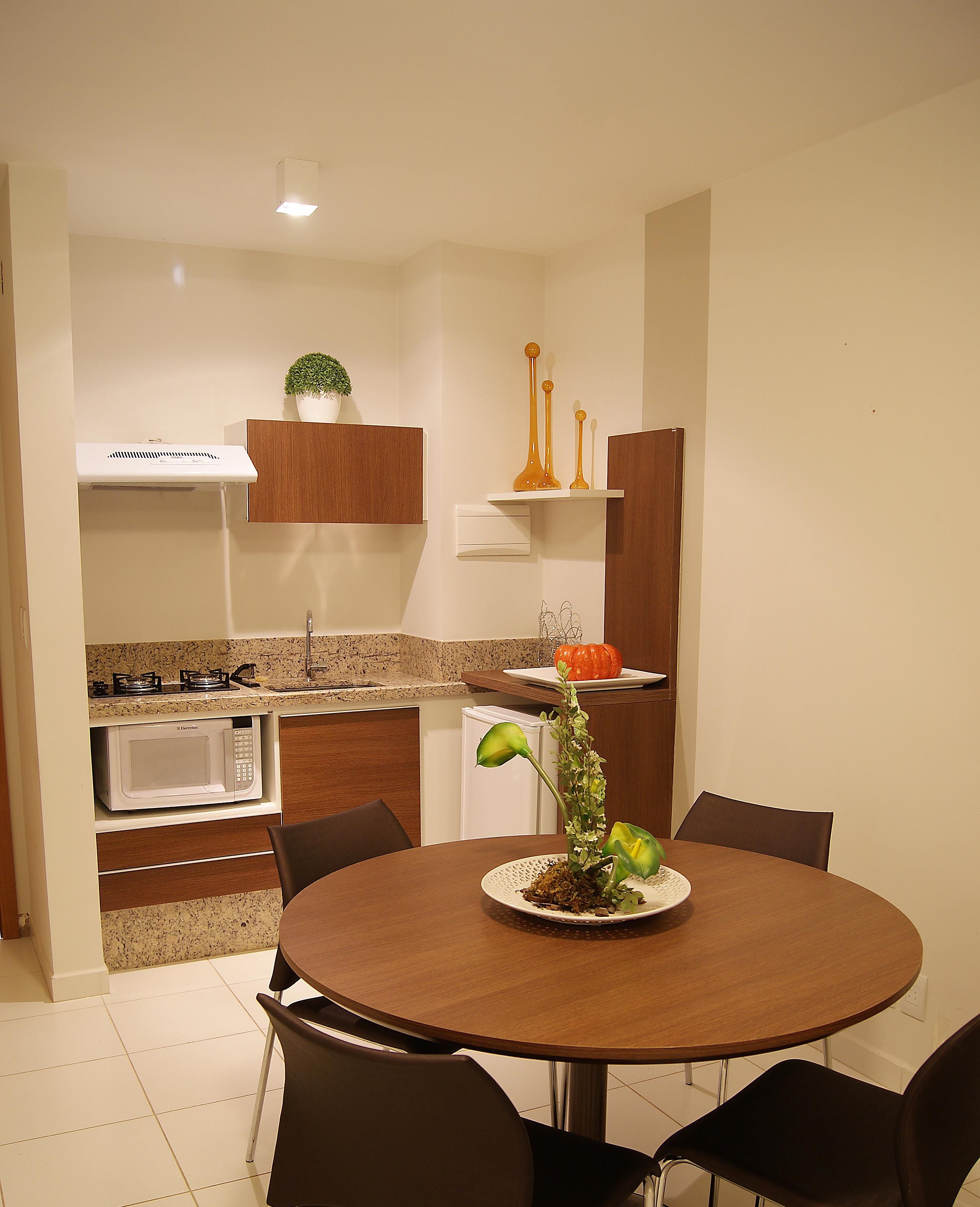 A compact kitchen with a dining area, including a microwave, stove, and a plant on the counter.