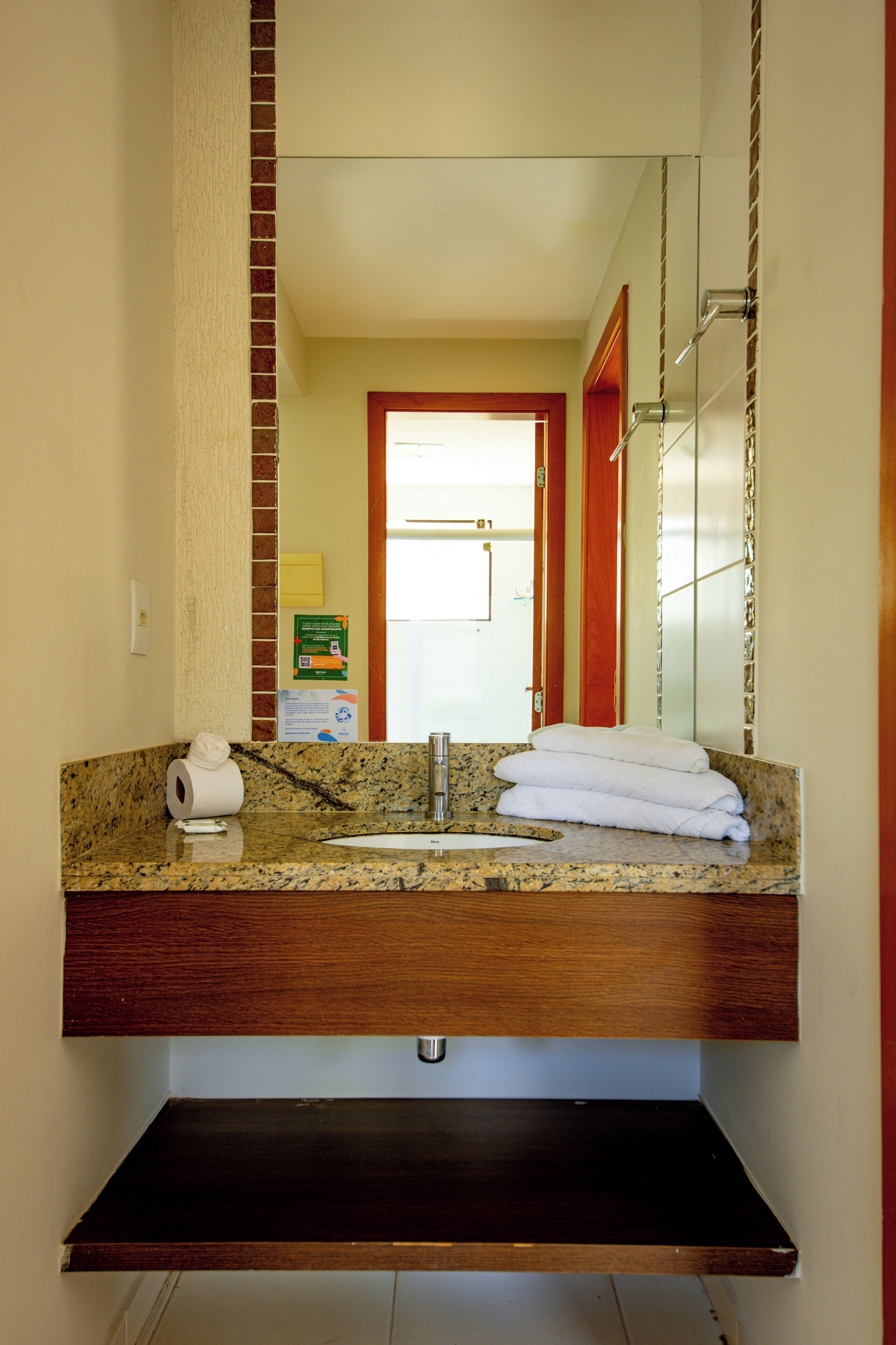 A bathroom with a granite countertop, a sink, a mirror, and a towel rack.